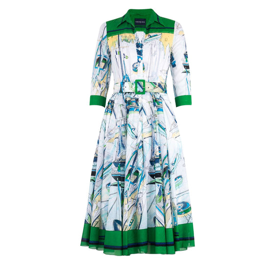 A white midi dress with an all-over abstract blue and yellow nautical print. The dress features a green-trimmed shirt collar, 3/4 sleeves with green cuffs, a button-front, a pleated A-line skirt with a green hem, and a matching fabric sash with a green end.